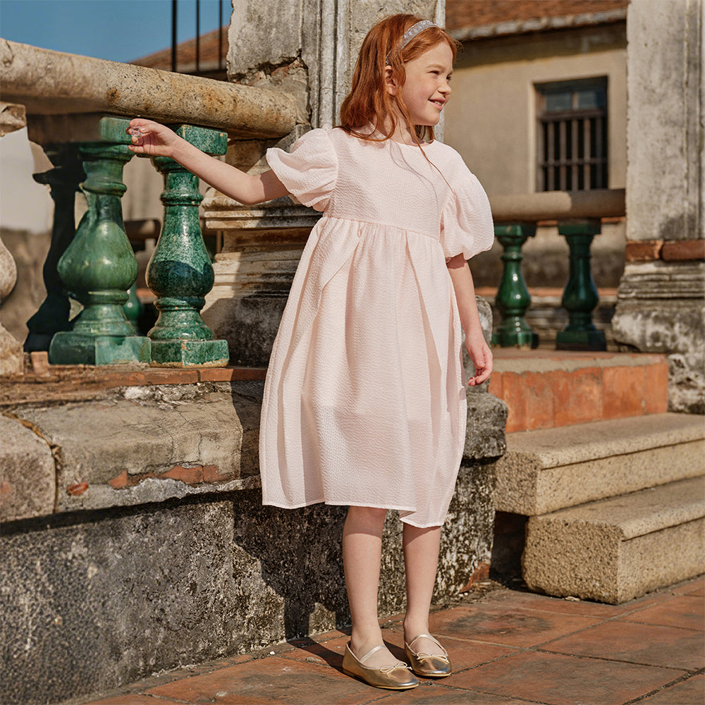 فستان بنات صيفي وردي فاتح بياقة دائرية وأكمام منفوشة من قماش محبك (ملمس بارز) بأسلوب أميرة